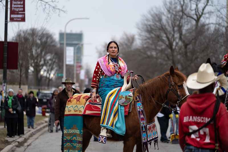Curator Nina Sanders, a visiting fellow at the Neubauer Collegium, sits on horseback at a parade to open Apsáalooke Women and Warriors on March 12, 2020. The exhibition grew out of the Open Fields research project, one of 111 faculty-led collaborations the Neubauer Collegium has supported since its 2012 launch. Photo by Max Herman.