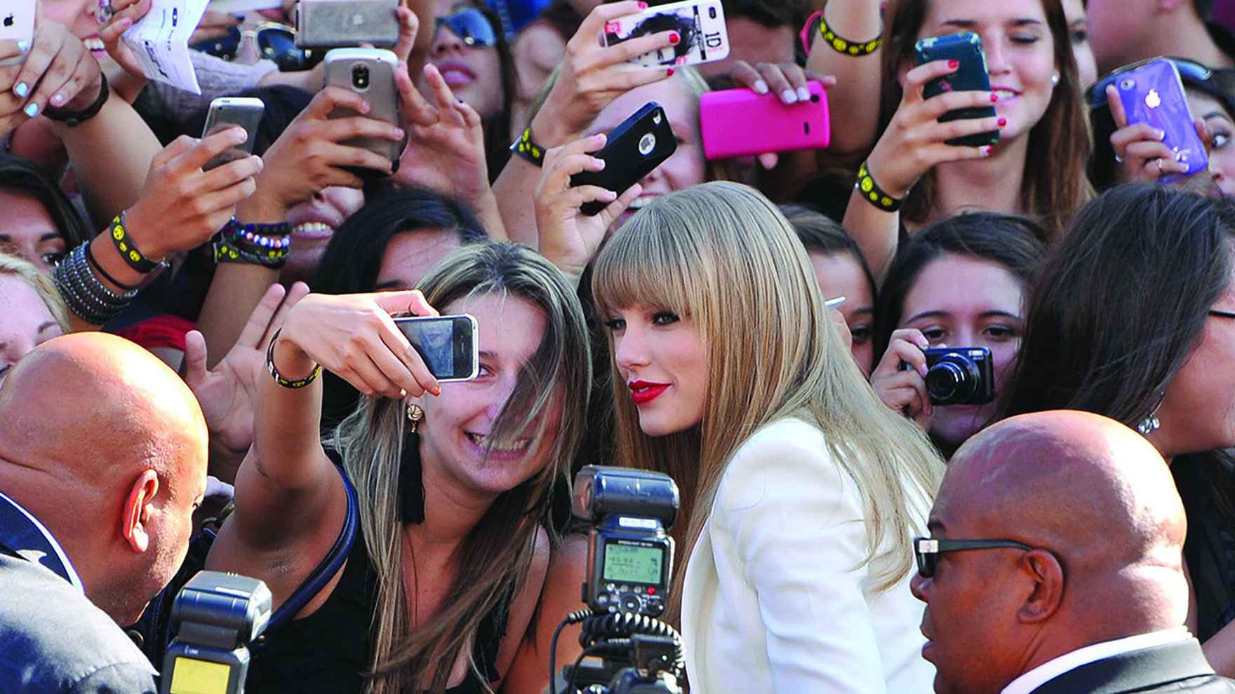 Taylor Swift poses for a selfie with a fan.